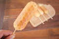 Homemade Waffle sausage sticks with hand holding on wooden table background . Trendy bakery street food