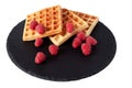 Homemade waffles with berries on black stone plate isolated. Belgian waffle with fruit raspberry on white background.