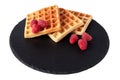 Homemade waffles with berries on black stone plate isolated. Belgian waffle with fruit raspberry on white background.