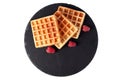 Homemade waffles with berries on black stone plate isolated. Belgian waffle with fruit raspberry on white background