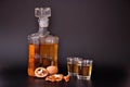 Homemade walnut brandy in a glass bottle and two glasses on a black background, several nuts next to it Royalty Free Stock Photo