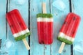 Homemade watermelon popsicles with ice against rustic blue wood