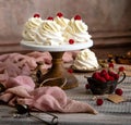 Homemade white mini desserts pavlova on wooden cake stand with whipped cream and raspberries on grey table with pink cloth Royalty Free Stock Photo