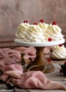 Homemade white mini desserts pavlova on wooden cake stand with whipped cream and raspberries on grey table with pink cloth Royalty Free Stock Photo