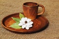 Coffee clay cup and original homemade flower from pumpkin seeds and bay leaves on round ceramic tray on rough homespun jute canvas