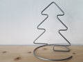 A homemade wire Christmas tree sits on a wooden shelf with white wallpaper symbolizing winter and snow. Royalty Free Stock Photo