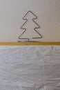 A homemade wire Christmas tree sits on a wooden shelf with white wallpaper symbolizing winter and snow. Royalty Free Stock Photo