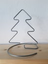 A homemade wire Christmas tree sits on a wooden shelf with white wallpaper symbolizing winter and snow. Royalty Free Stock Photo