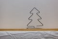 A homemade wire Christmas tree sits on a wooden shelf with white wallpaper symbolizing winter and snow. Royalty Free Stock Photo