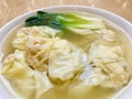 Shrimp Wanton Noodle Soup with vegetable in a white bowl on at wooden brown table. close up.