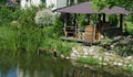 Homemade wooden gazebo on the shore of a village pond