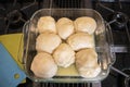 Homemade yeast rolls in glass dish with melted butter sitting on a stovetop with colorful silicon potholders nearby