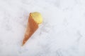 Homemade yellow ice cream in wafer cone on grey background. Selective focus, copy space Royalty Free Stock Photo