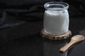 Homemade yoghurt with a wooden spoon on a black kitchen counter, close up, isolated