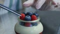Homemade yogurt with blueberries in a glass jar. Hand putting Strawberry in Yogurt
