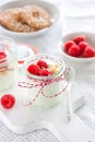Homemade yogurt dessert with raspberries and crushed cookies in a small jar on a kitchen background Royalty Free Stock Photo