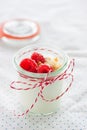 Homemade yogurt dessert with raspberries and crushed cookies in a small jar on a kitchen background Royalty Free Stock Photo