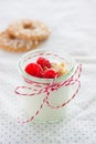 Homemade yogurt dessert with raspberries and crushed cookies in a small jar on a kitchen background Royalty Free Stock Photo