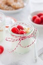 Homemade yogurt dessert with raspberries and crushed cookies in a small jar on a kitchen background Royalty Free Stock Photo