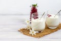 Homemade yogurt in two glasses on a light wooden background. Decorated with mint and cranberry berries. Healthy diet food.