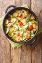 Homemade zucchini gratin with cheese and tomatoes close-up in a pan. vertical top view