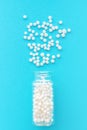 Homeopathic globules in glass bottle on pastel blue background. The globules are scattered from bottle. Alternative homeopathy Royalty Free Stock Photo