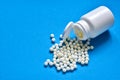 Homeopathic globules and plastic bottle on blue background. Healtcare and pills concept. Vitamins, prebiotics, probiotics. Flat l