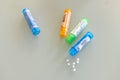 Homeopathic globules scattered around with their colored containers Royalty Free Stock Photo