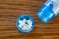 Homeopathic globules scattered around with their colored containers on a wooden table