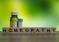 Homeopathic medicine bottles with concept image of homeopathy word on brown surface and green mix yellow background Royalty Free Stock Photo