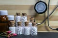 Homeopathic medicine bottles in a row consisting of pills, Stethoscope and pink flower bud on wood and dark background. Natural Royalty Free Stock Photo