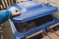 Homeowner about to discard cardboard into a council blue recycling bin outside his home.