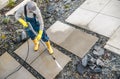 Homeowner Washing Out Dirt From His Garden Concrete Paths Using Pressure Washer