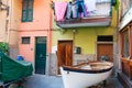 Homes entrance doors at end of lane with classic style Mediterranean fishing boat pulled up and laundry over balcony railing