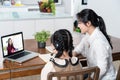 Homeschool Asian little young girl learning online class from school teacher by digital remote internet meeting due to coronavirus Royalty Free Stock Photo