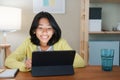 Homeschooling, Asian girl doing homework and online learning with tutor on the tablet digital while sitting  at a desk at night Royalty Free Stock Photo