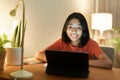 Homeschooling, Asian girl doing homework and online learning with tutor on the tablet digital while sitting  at a desk at night Royalty Free Stock Photo