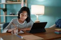 Homeschooling Asian girl doing homework And study online with tablet at a desk at night