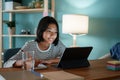 Homeschooling Asian girl doing homework And study online with tutor on tablet at desk at night Royalty Free Stock Photo