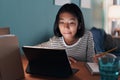 Homeschooling. Asian girl is studying online with tablet at desk at night