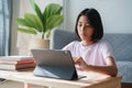 Homeschooling. Asian girl is studying online with teacher via the internet on tablet and doing homework at home morning and sunlig Royalty Free Stock Photo