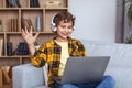Homeschooling concept. Cute little boy wearing headset video chatting with teacher via laptop, waving hand and smiling Royalty Free Stock Photo