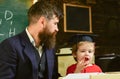 Homeschooling concept. Enthusiastic kid studying with teacher. Father checking homework, helps to boy, son. Teacher in Royalty Free Stock Photo