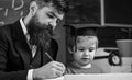 Homeschooling concept. Enthusiastic kid studying with teacher. Father checking homework, helps to boy, son. Teacher in Royalty Free Stock Photo