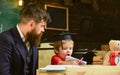 Homeschooling concept. Enthusiastic kid studying with teacher. Father checking homework, helps to boy, son. Teacher in Royalty Free Stock Photo