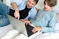 Homeschooling, home education concept. Father and teenager son looking at laptop screen, wathing video or communicate online in