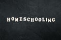 Homeschooling word made of wooden letters on a black background, top view.