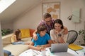 Homeschooling. Young positive parents helping his son with homework while little cute girl sitting on sofa on the Royalty Free Stock Photo