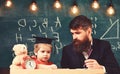 Hometask concept. Enthusiastic kid studying with teacher. Teacher in formal wear and pupil in mortarboard in classroom Royalty Free Stock Photo