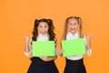 Homework done. Happy small children holding empty homework sheets on yellow background. Cute little girls smiling with